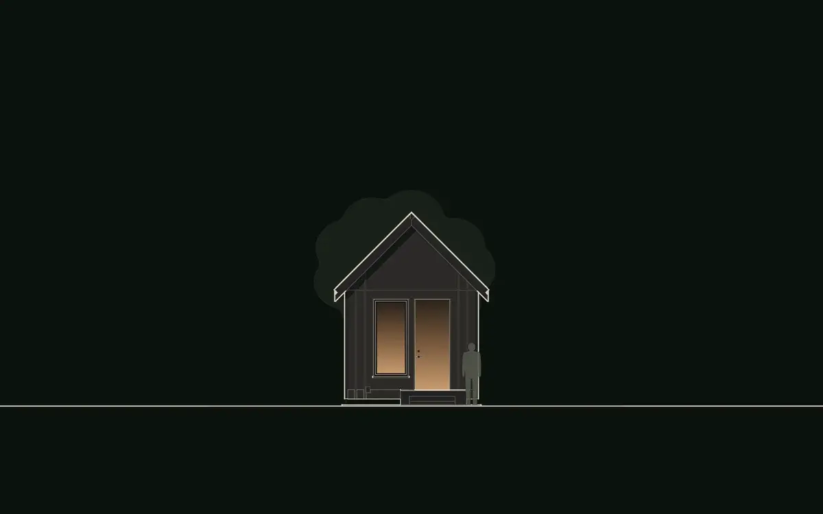Front elevation drawing of The Wolf: the glass entry gable of the 12 × 20 studio, a full-lite door and a tall window in near-black board-and-batten walls under a steep black 12:12 standing-seam roof, with a stoop. The Wolf, a small studio plan with a loft by House of KNA.